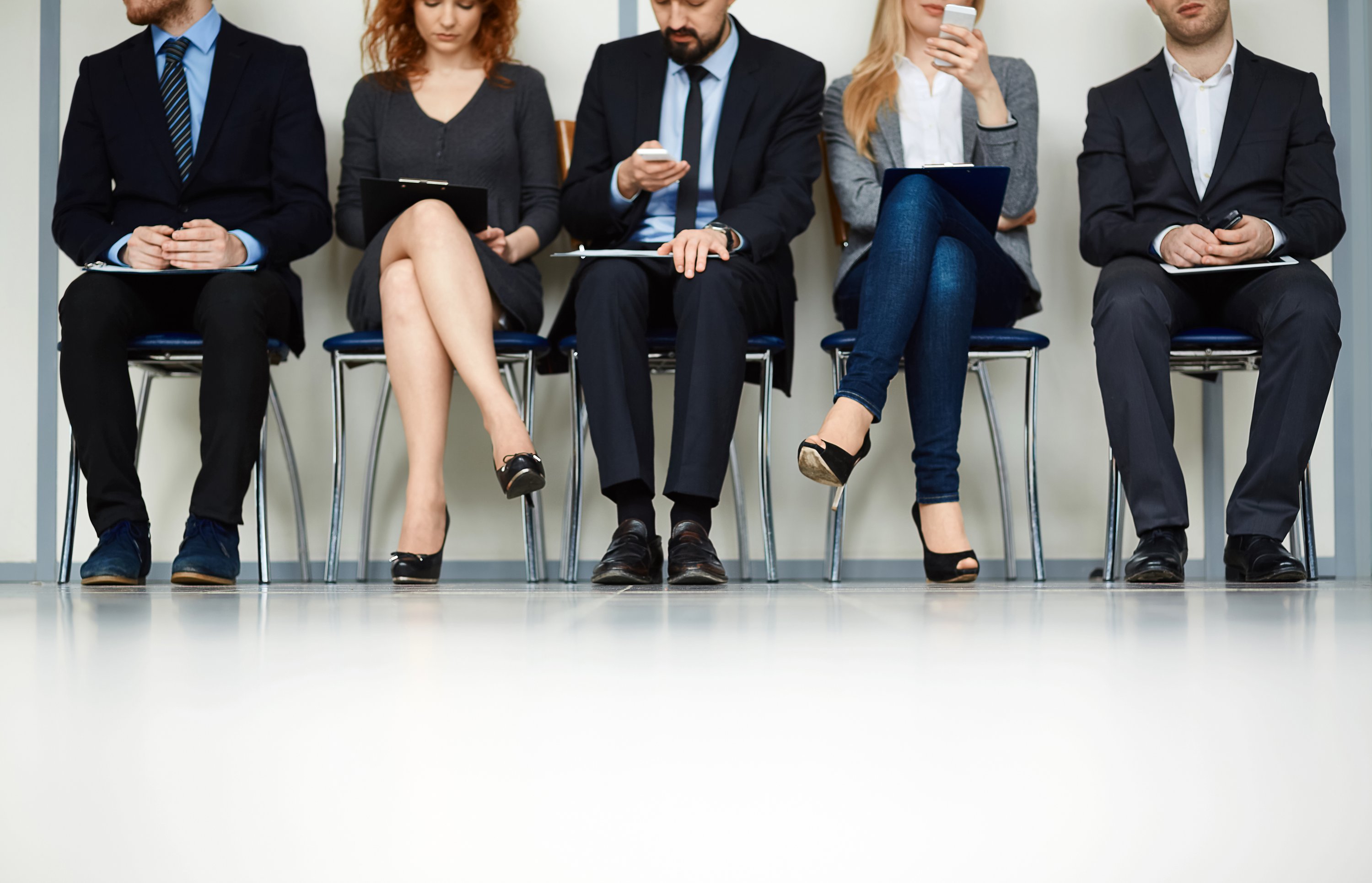 line-of-young-people-sitting-by-wall-while-waiting-for-their-turn-for-interview-SBI-300723797